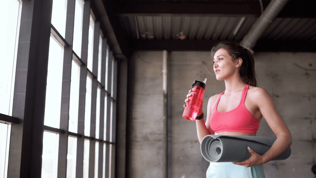 Het meisje stopt een fles water en tapijt